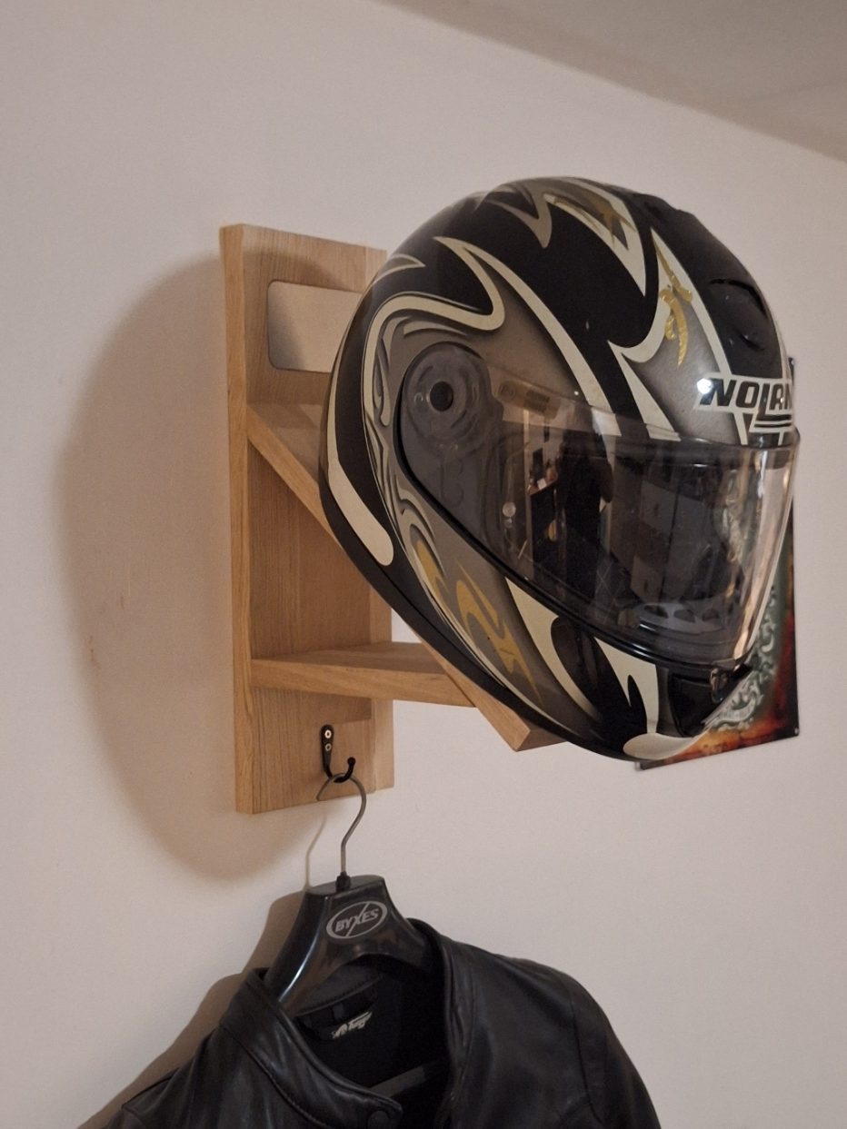 Support mural pour casque moto – vue de gauche en situation, avec casque intégrale et blouson en cuir suspendus.