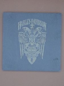Sous verre en ardoise gravé au laser représentant le logo Harley-Davidson avec aigle aux ailes déployées, tête de mort et épée centrale